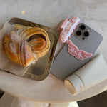 Angel Hold Plushie Sticker Angel Hold Plushie Sticker on phone with angel hold styling cream, sweetheart clip, and pastry on table