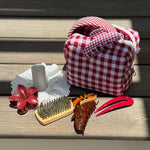 Gingham Pouch in Cherry Kiss Gingham Pouch in Cherry Kiss on wood with assorted hair care, accessories, and styling tools