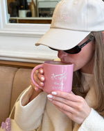 model drinking out of emi jay mug while wearing emi jay dad hat with sweetheart clip attached to purse strap