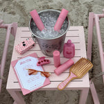 Bamboo Paddle Brush in Lychee Baby aura hair + body mists in Lychee Baby in ice bucket on table with camera, menu, sunglasses, lotion, hair clip, and bambo brush