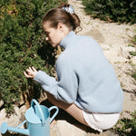 Big Effing Clip in Blue Dream model sitting outside next to watering can with Big Effing Clip in Blue Dream in hair