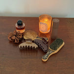 Big Effing Clip in Fireside Assorted Emi Jay hair accessories and styling tools with candle and Aura Hair + Body Mist in Toasted Sugar.