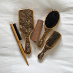 Flat Brush in Toasted Sugar Assorted Emi Jay hair brushes with Aura Hair + Body Mist in Toasted Sugar on bed.