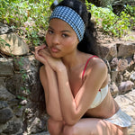 Infinity Headband in Navy Gingham model sitting next to rocks with chin on hands and Infinity Headband in Navy Gingham in hair