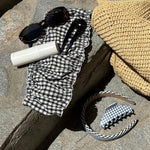 Halo Headband in Navy Gingham assorted hair care and accessories on stone steps with bag and sunglasses