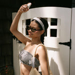 Halo Headband in Navy Gingham model spraying aura hair mist in hair while wearing Halo Headband in Navy Gingham