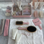 Infinity Headband in Blush assorted emi jay hair care and accessories with emi jay towel, mirror, and vanity case on marble
