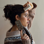 Mini Boar Bristle Brush in Toasted Sugar Model applying Angelstick to hair while holding Mini Boar Bristle Bamboo Brush in Toasted Sugar.