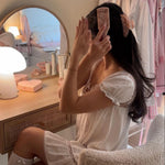 Mini Boar Bristle Brush in Pink Chantilly model sitting in front of vanity brushing hair with Mini Boar Bristle Brush in Pink Chantilly