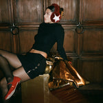 Sugar Muffs in Red Currant model leaning on oversized gift while wearing Sugar Muffs in Red Currant