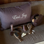 Hair Pin in Tortoise Bow Assorted hair care, accessories, and pouch next to Emi Jay embroidered pillow on couch.