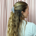 Sweetheart Clip in Lilac Sky model standing in front of pink curtain with Sweetheart Clip in Lilac Sky in hair