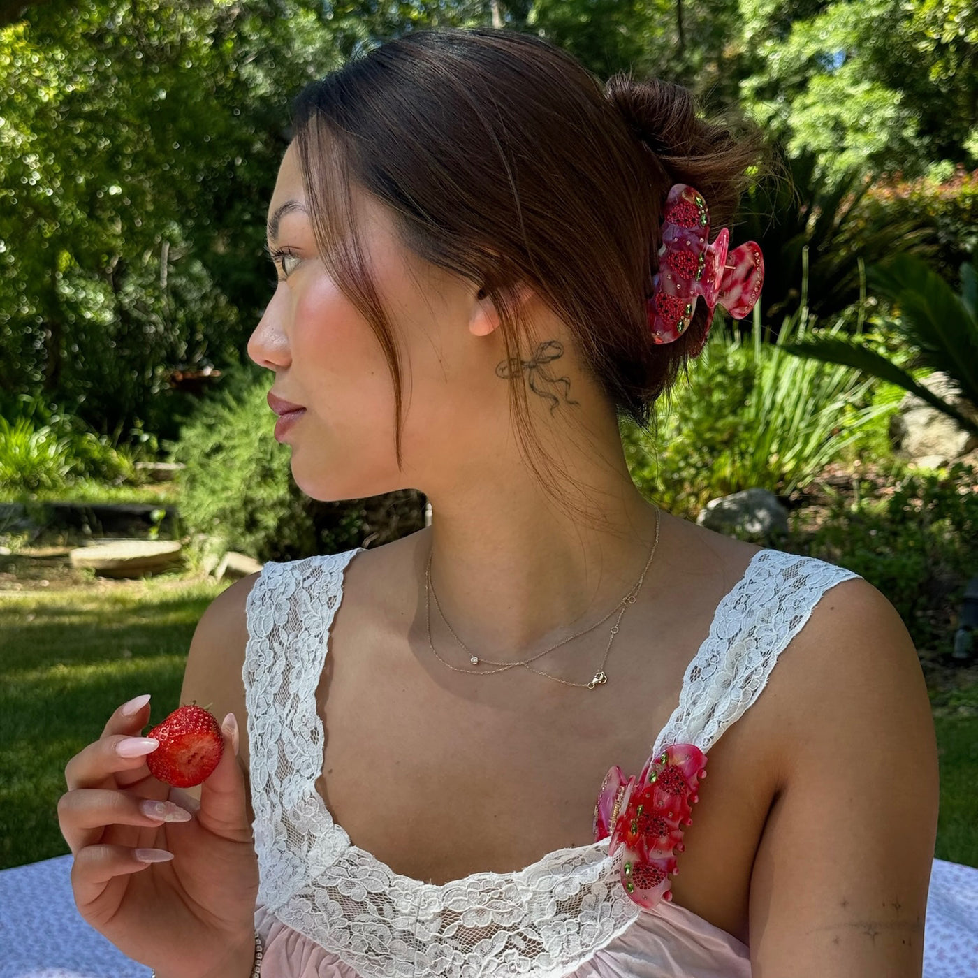 model holding strawberry with Sweetheart Clip in Strawberry Glow in hair