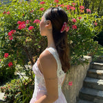 Sweetheart Clip in Strawberry Glow model standing in front of flowers with Sweetheart Clip in Strawberry Glow in hair