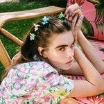 Baby Daisy Clip Set in Jade model leaning on chair with Baby Daisy Clip Set in Jade + Petal + Aqua in hair