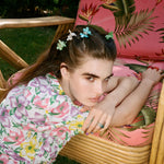 Baby Daisy Clip Set in Petal model leaning on chair with Baby Daisy Clip Set in Petal + Aqua + Jade in hair