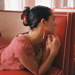 Big Effing Clip in Cherry Kiss model laying in booth while showing how to wear Big Effing Clip in Cherry Kiss in hair