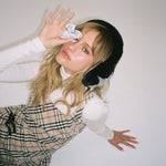 Sweetheart Clip in Plaid Princess model holding Sweetheart Clip in Santa's Helper while wearing Sugar Muffs in Black Diamond