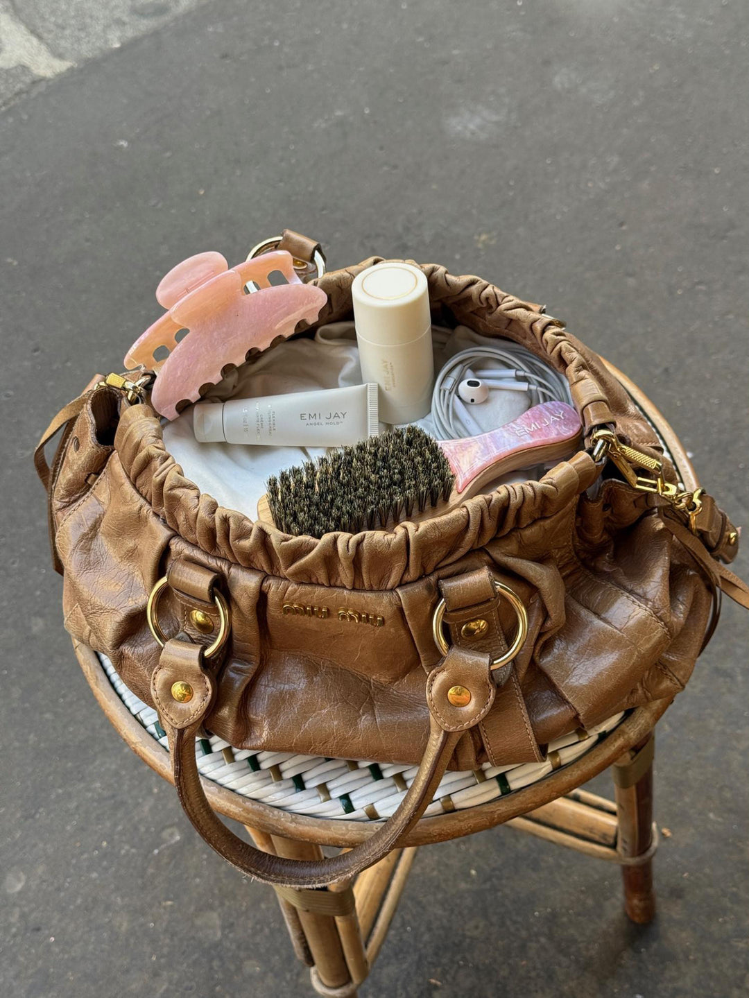 assorted Emi Jay hair care and accessories in brown purse on table 