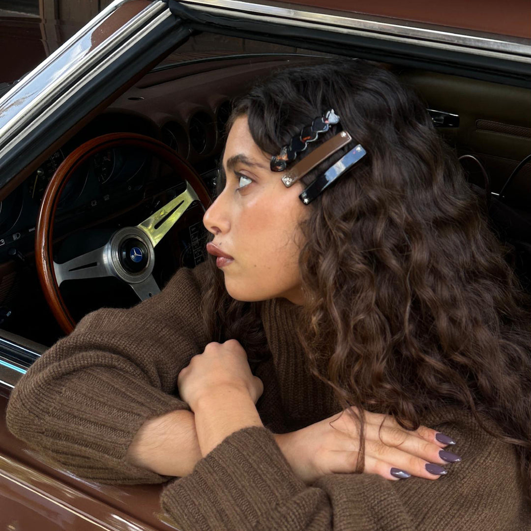 Model sitting in car with arms crossed wearing Barrette Set in Bear Hug in hair.