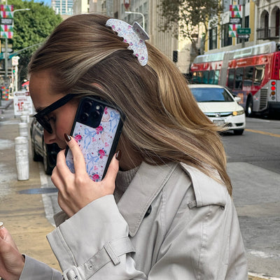 closeup of model wearing Big Effing Clip in Lovey Dovey while using a phone with a Wildflower case