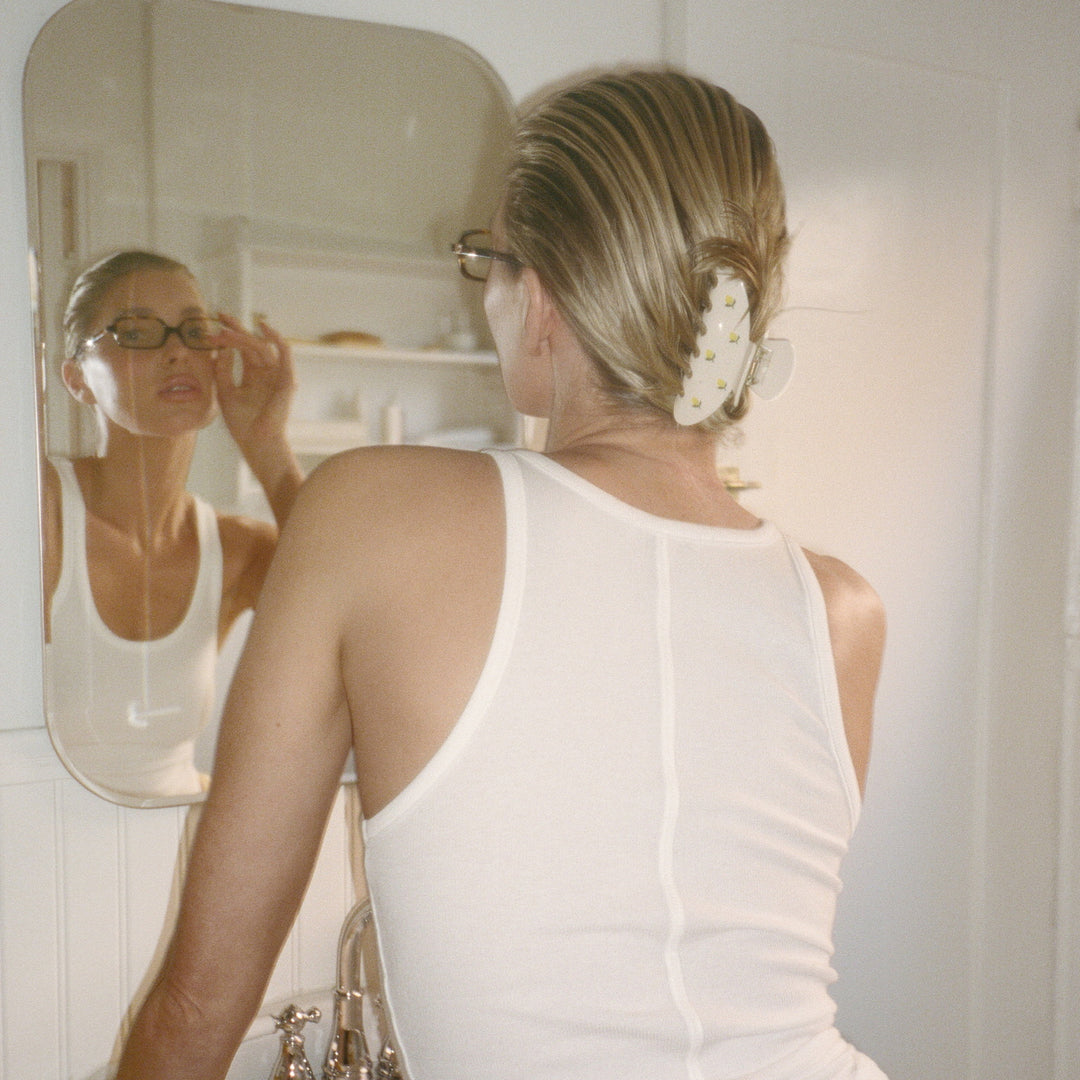 elsa hosk looking in bathroom mirror while wearing big effing clip in lemon gelato in hair