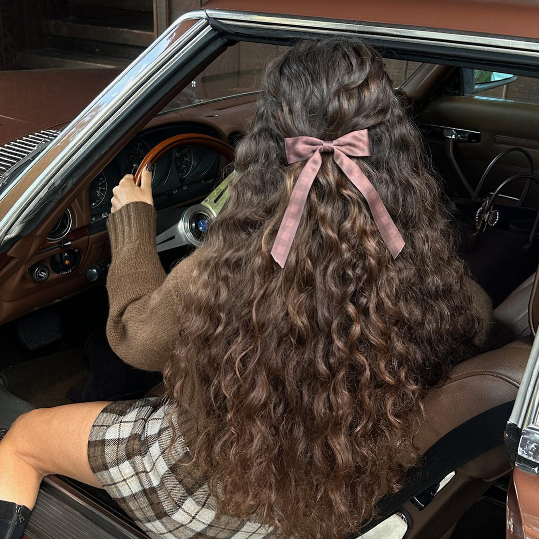 Closeup of model sitting in car wearing bow barrette in fireside.