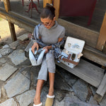 olivia jade opening Cozy Pouch in Dream Cloud Knit while sitting next to vanity cases with assorted emi jay hair care and accessories