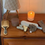 assorted emi jay hair care and accessories on side table with candle and lamp