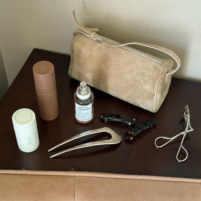 Assorted Emi Jay hair care and accessories with styling tools and bag on table.