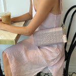 model wearing purse with mini angelstick + keychain sitting at table with iced coffee