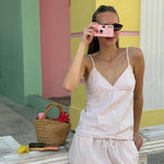 model using Lychee Baby Disposable Camera while standing next to bag with aura hair + body mist in lychee baby and assorted hair accessories 