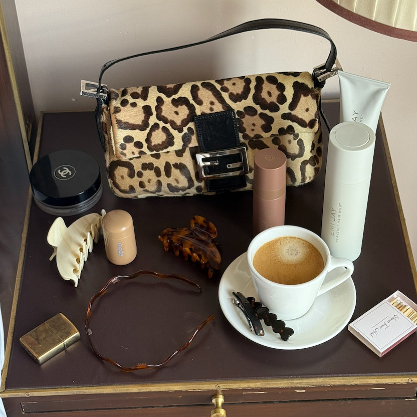 Assorted Emi Jay hair care and accessories with purse and coffee on table.