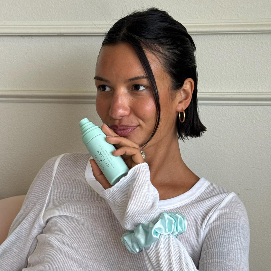 model holding aura hair + body mist while wearing Sweet Dreams Silk Scrunchie in Mint Mochi Sky on wrist