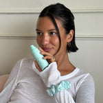 model holding aura hair + body mist while wearing Sweet Dreams Silk Scrunchie in Mint Mochi Sky on wrist