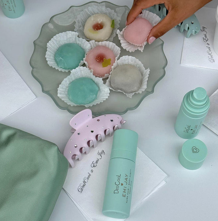 model reaching for mochi treat on tray next to aura mists and big effing clip in pink mochi sky