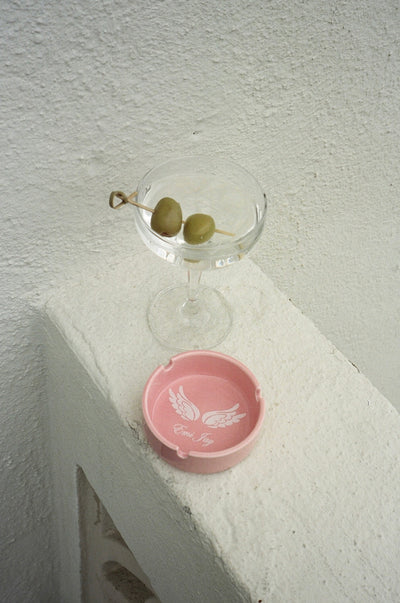 angelstick ashtray next to a cocktail glass with green olives