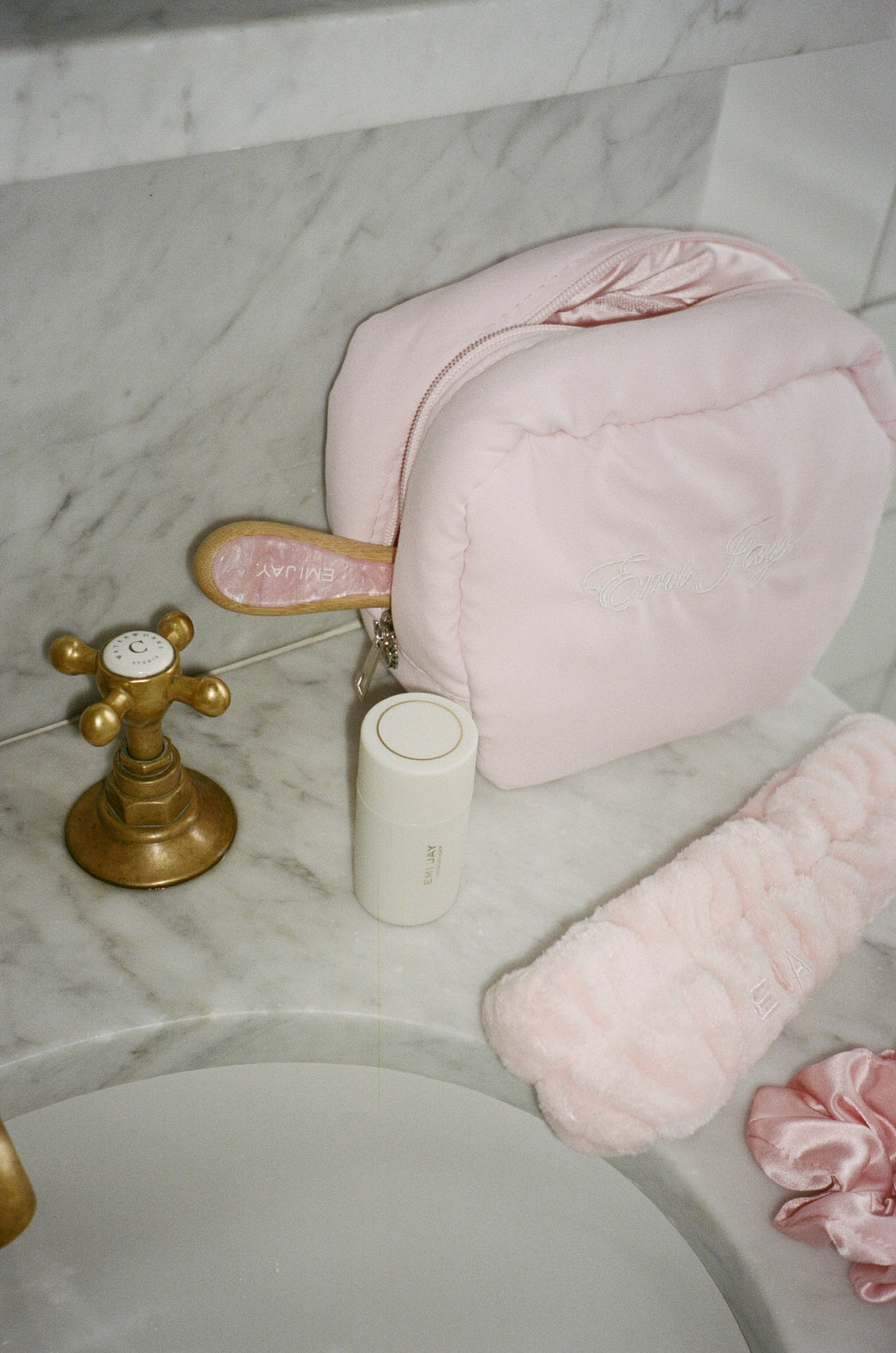 angelstick on sink next to angelstick pouch, cloud headband, silk scrunchie, and flat brush in pink sugar