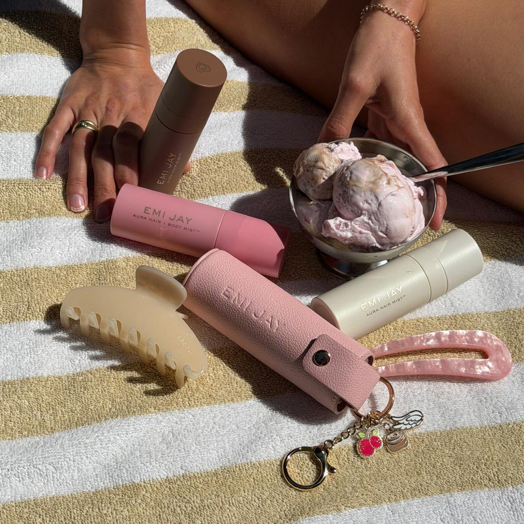 Aura Hair + Body Mist™ Keychain with aura hair + body mists, hair pin, and big effing clip next to bowl of ice cream and model on yellow and white striped towel