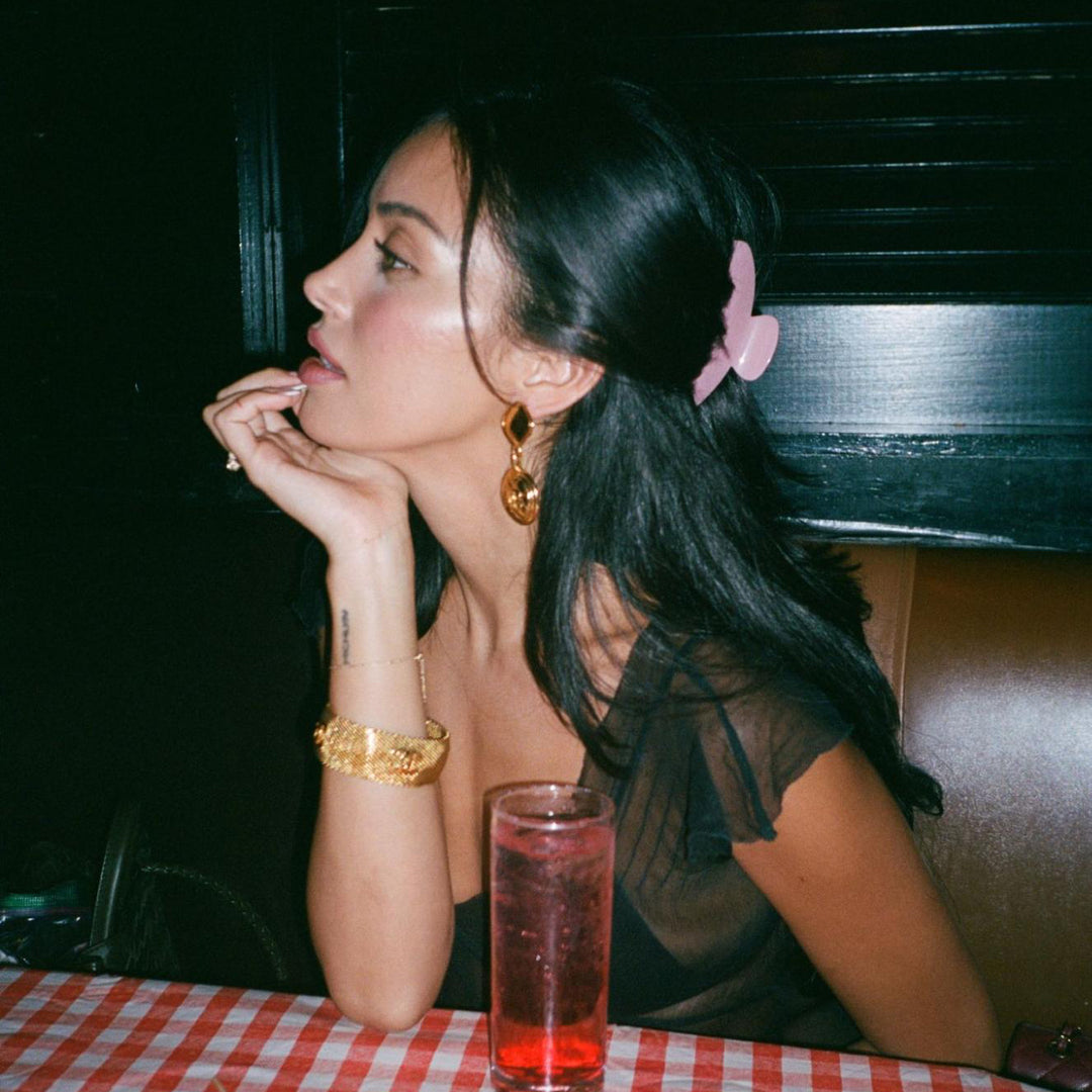 model looking away from drink with hand on chin while sitting at table with Big Effing Clip in Baby Mauve in hair
