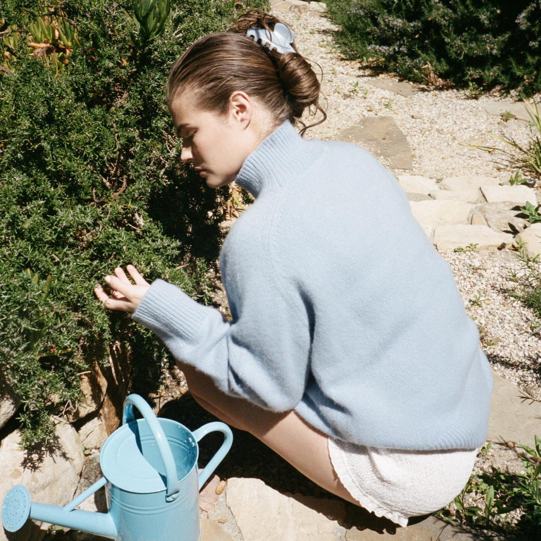 model sitting outside next to watering can with Big Effing Clip in Blue Dream in hair