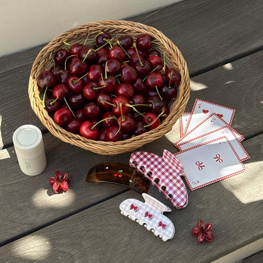 assorted hair claw clips, hair care, playing cards, and cherries in a basket.