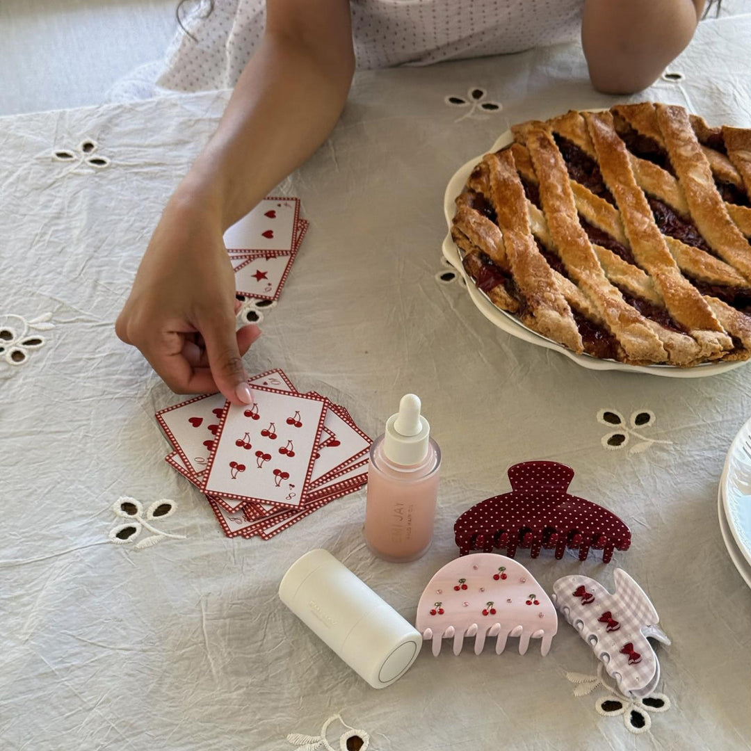 model playing cards on table next to cherry pie, hair care, and claw clips