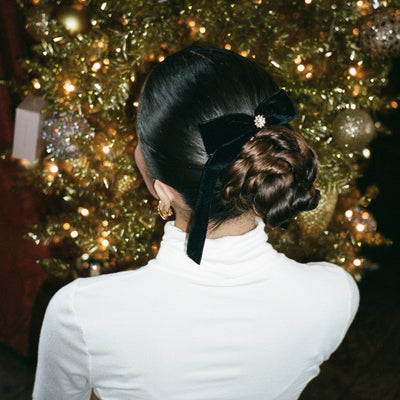 model standing in front of Christmas tree wearing Bow Barrette in Iconic Velvet in hair