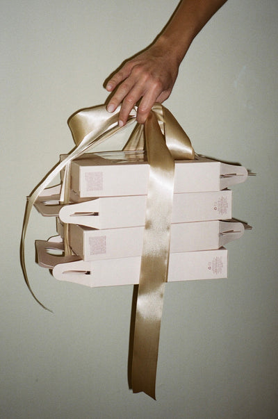 model holding gold ribbon wrapped around 4 angel hair kit gift sets