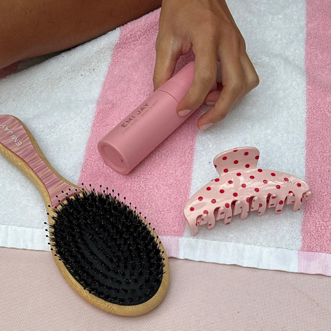 model holding aura hair + body mist in lychee baby next to claw clip and hair brush