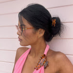 model wearing Hair Pin in Tortoise Hibiscus in hair and big effing clip in tortoise clipped to pink bikini top