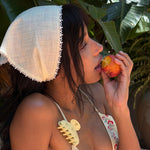 model wearing head scarf eating fruit with lil effing clip attached to strap