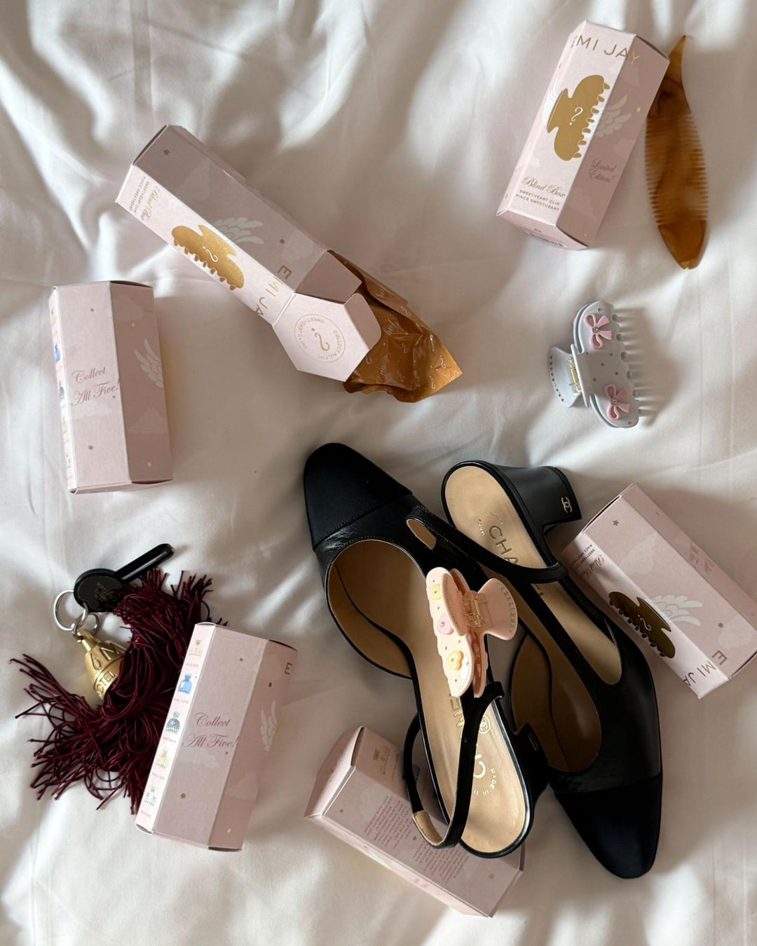 assorted blind boxes and sweetheart clips on bed with shoes and keys