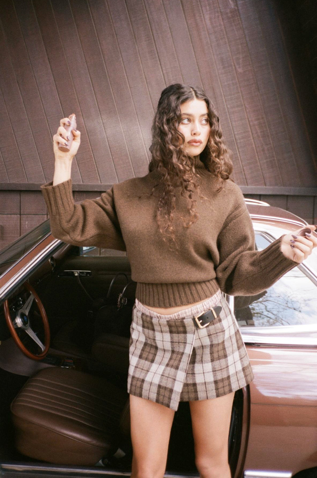 Model standing in front of car while using Aura Hair + Body Mist in Toasted Sugar.